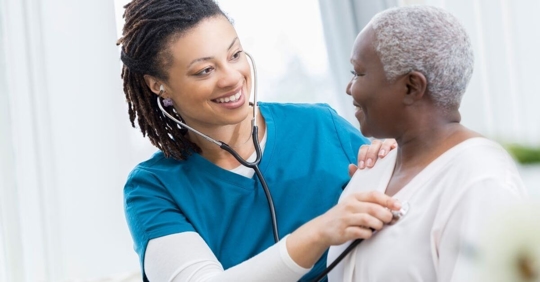 nurse with stethoscope checking elder patient's lungs