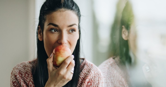 Woman eating an apple as part of her new personalized wellness plan with PrimeHealth Asheville