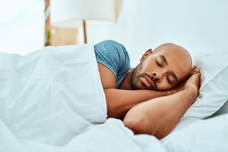 man-with-shaved-head-sleeping-in-bed